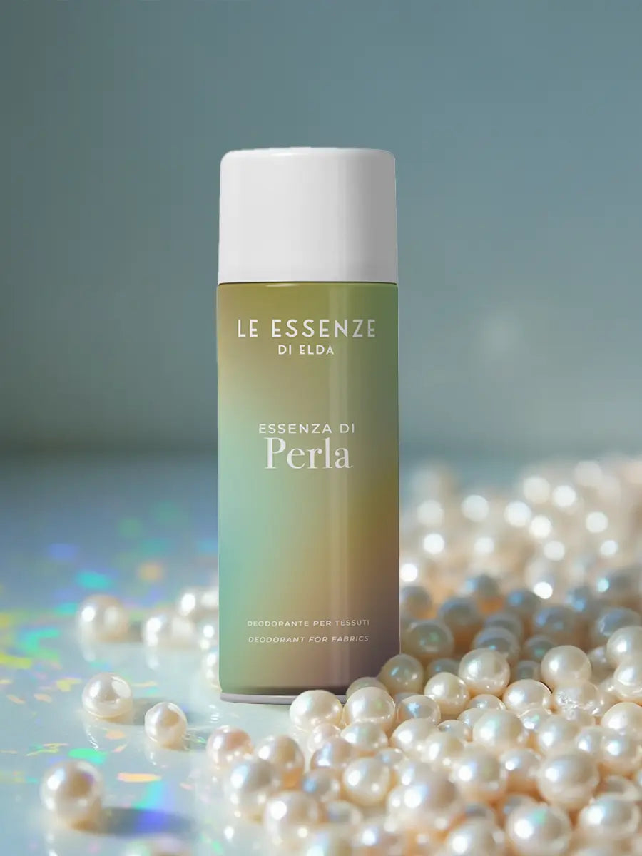 Deodorant bottle labeled 'Le Essenze di Elda' surrounded by pearls on a reflective surface.