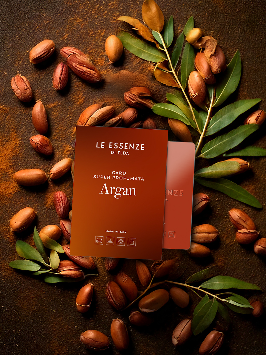 Le Essenze di Elda Argan card surrounded by argan seeds and leaves on a dark surface